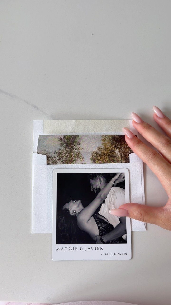 Polaroid-style save the date card with a black and white couple photo on marble.
