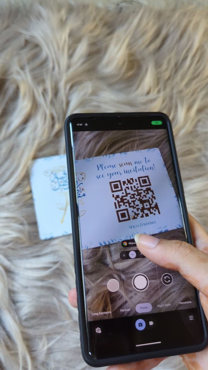 Smartphone scanning a blue save the date card featuring a prominent QR code