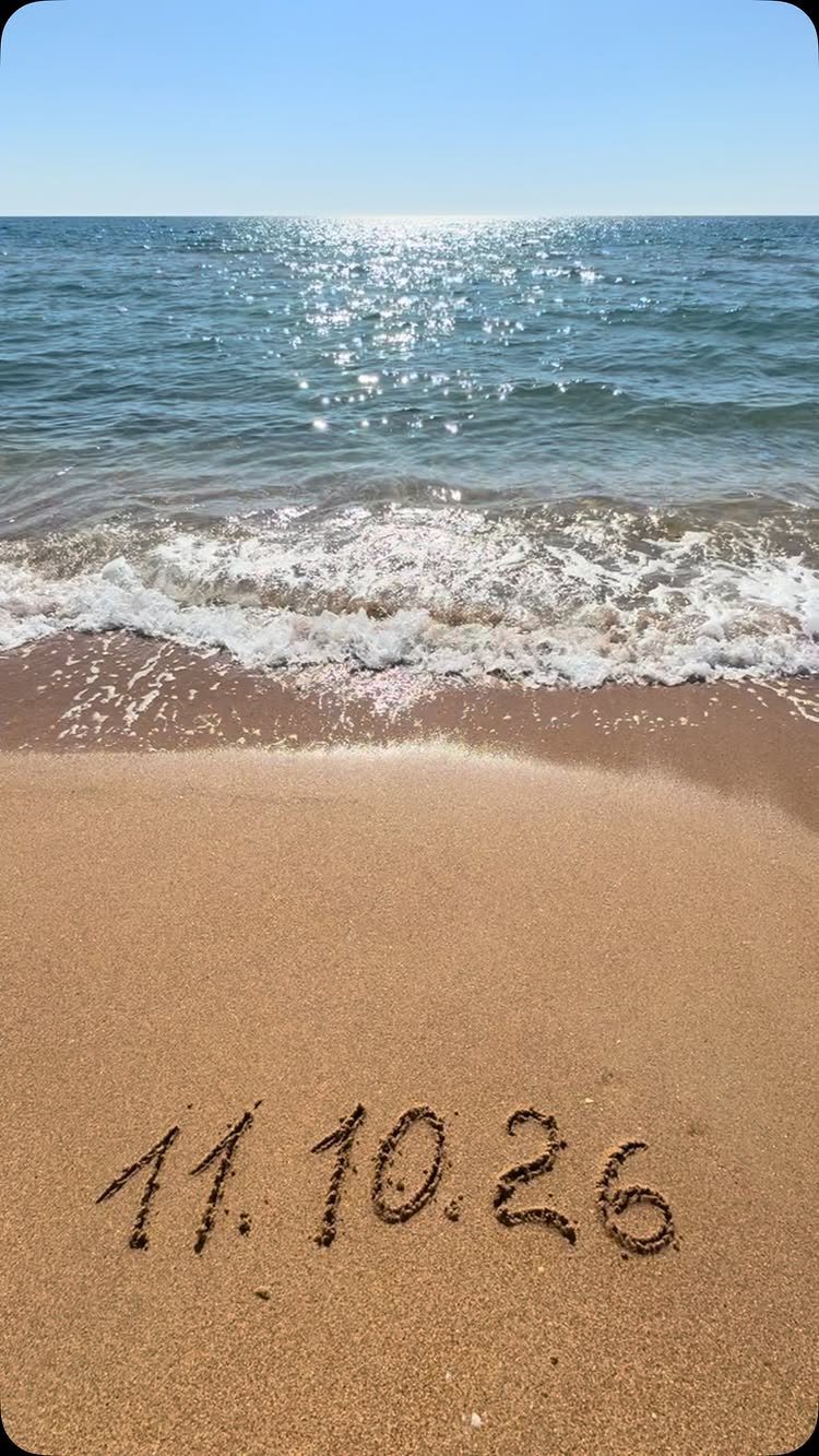 Date 11.10.26 written in beach sand with ocean waves in the background