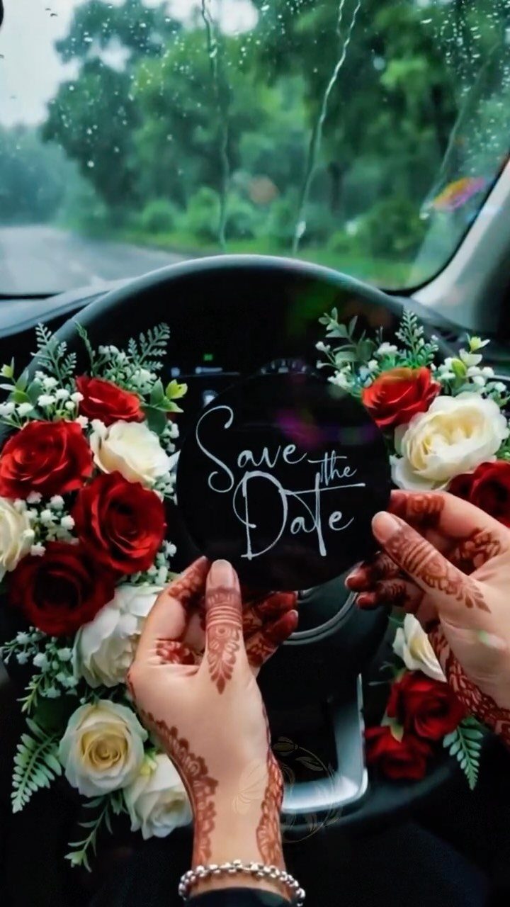 Hands with henna holding a Save the Date sign amidst roses in a car
