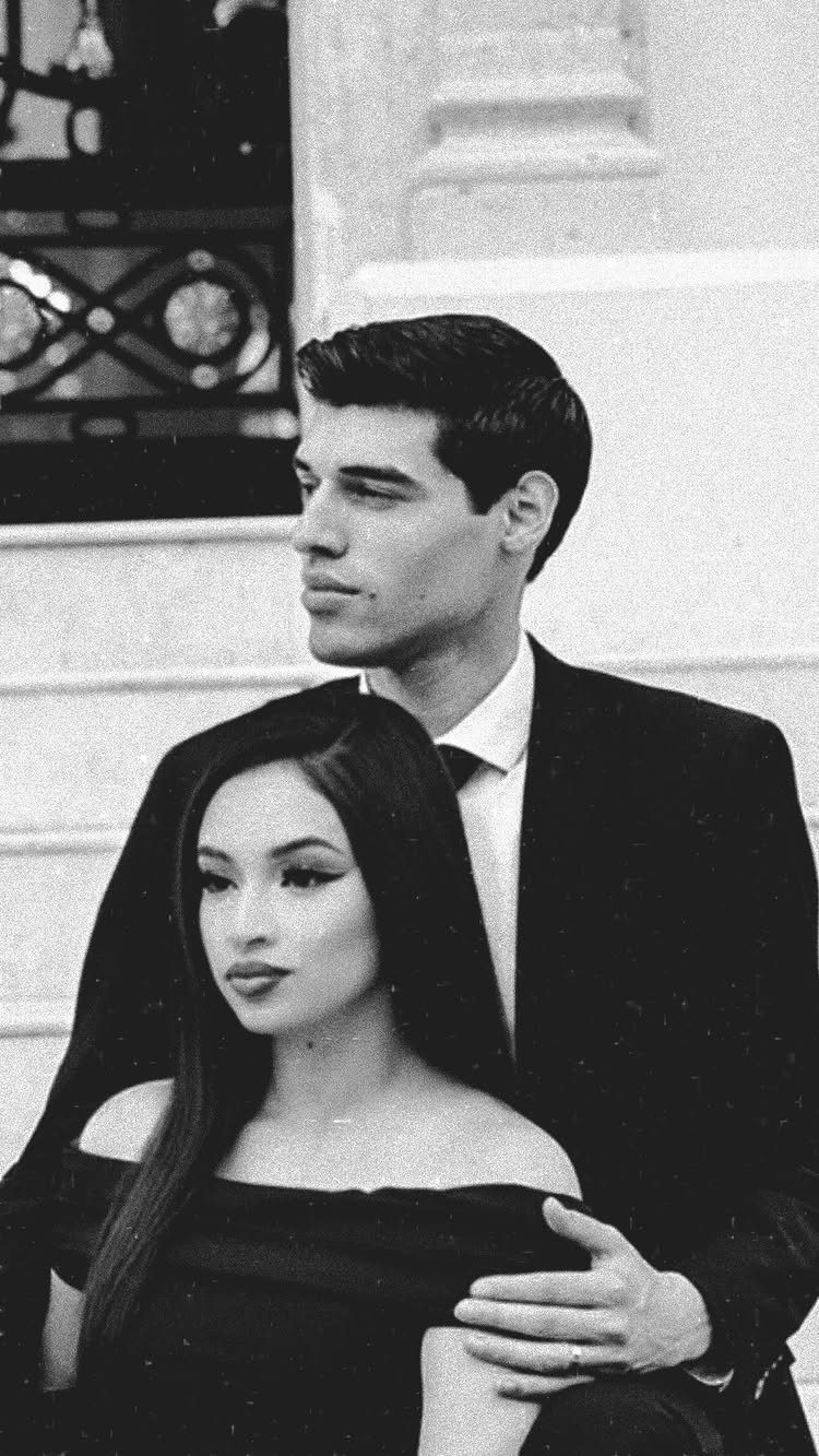 Young couple in formal attire posing for a black and white portrait outdoors.