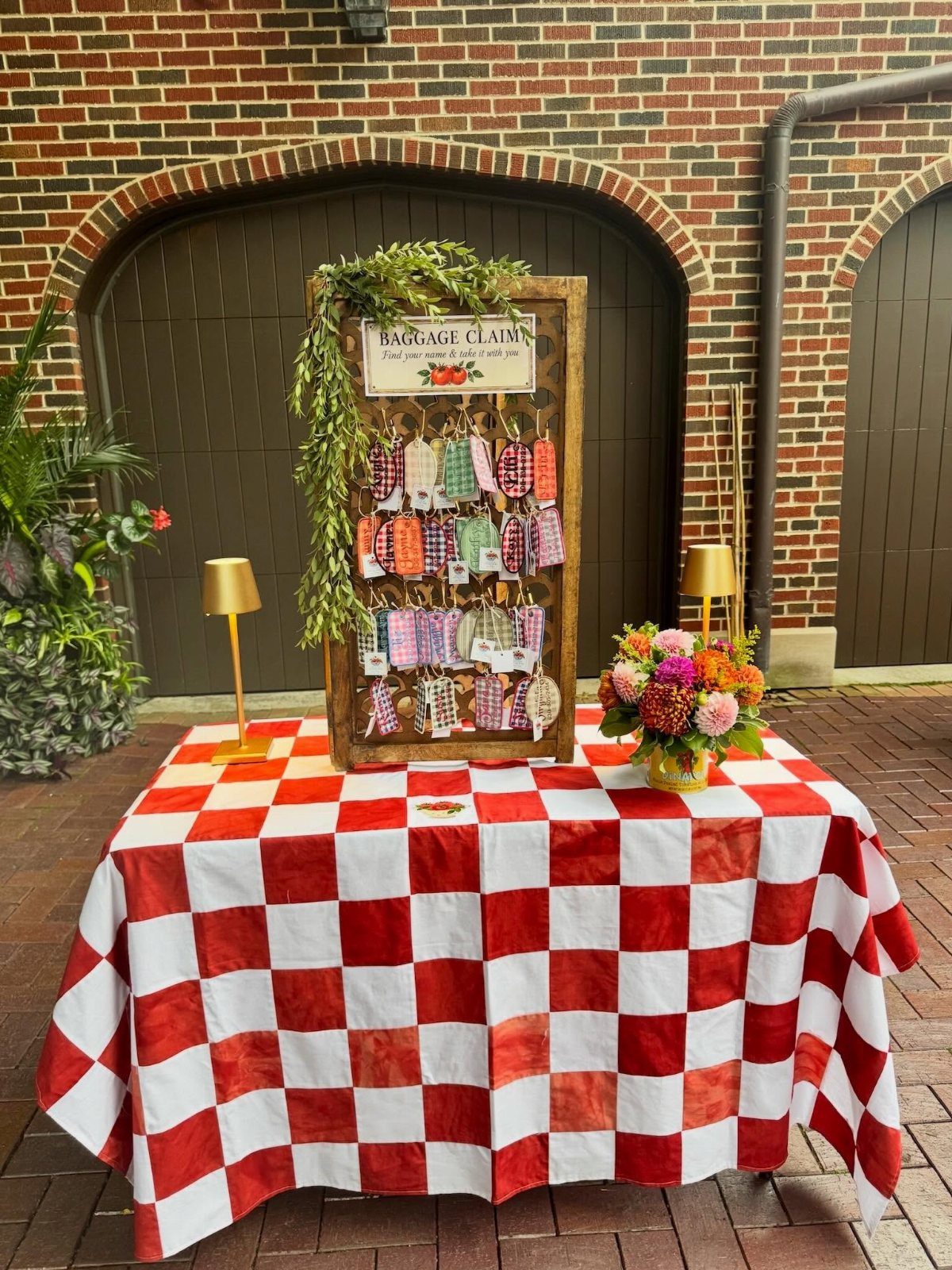 Luggage tags hanging on a wooden display board atop a red checkered table.