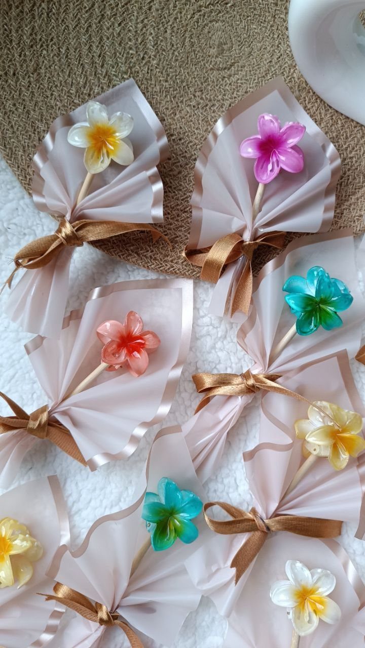 Flower-shaped candies wrapped in white paper and brown ribbons as party prizes.