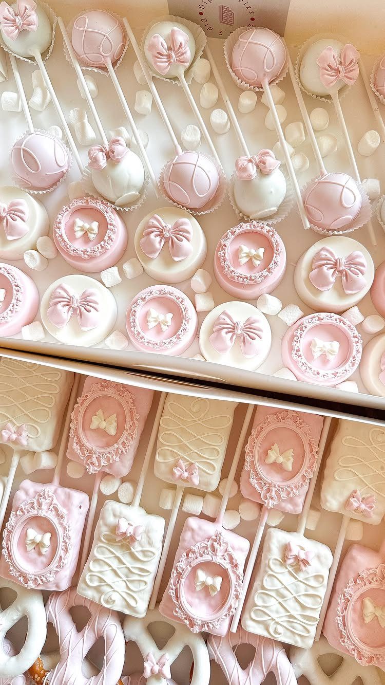 Pink and white decorated cake pops and chocolate treats in white gift boxes.