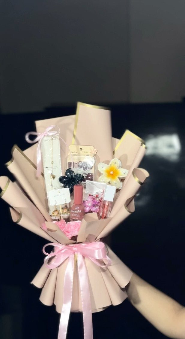 Mini bouquet wrap containing beauty products and a flower tied with pink ribbon.