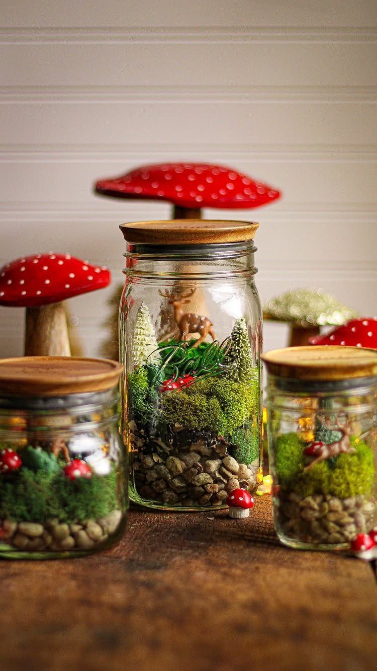 Miniature terrariums in glass jars with moss, pebbles, and tiny deer figurines.