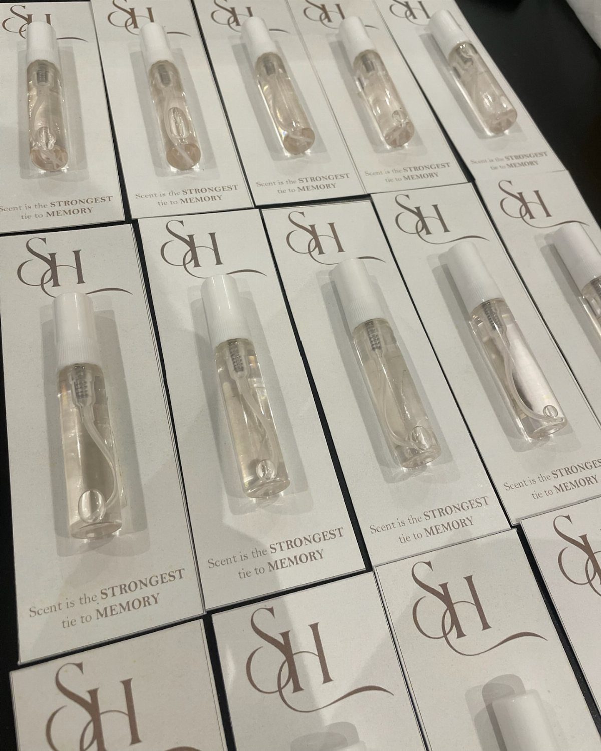 Small perfume vials in white cardboard sleeves arranged in a grid pattern.