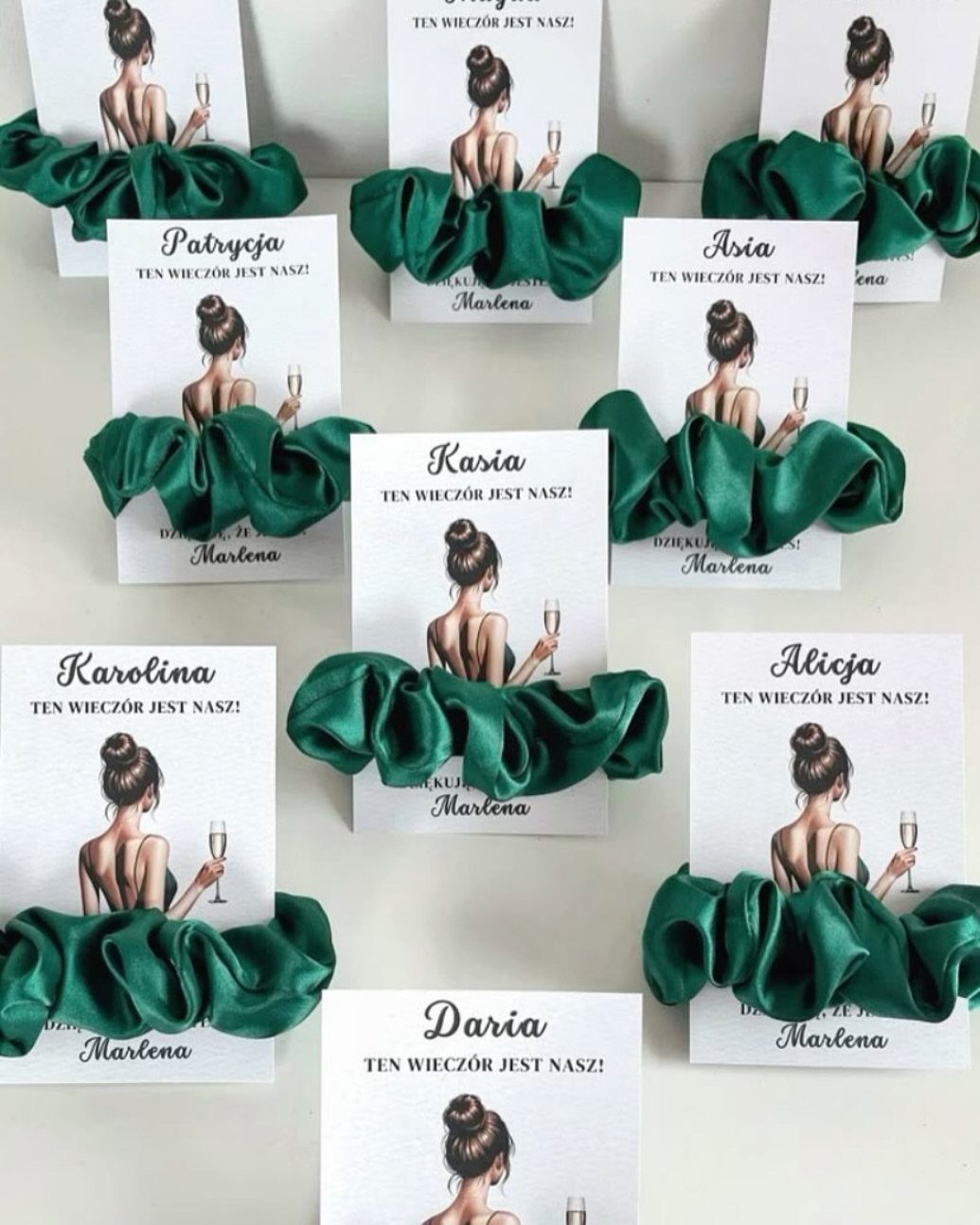 Dark green silky scrunchies wrapped around personalized white gift cards with illustrations.