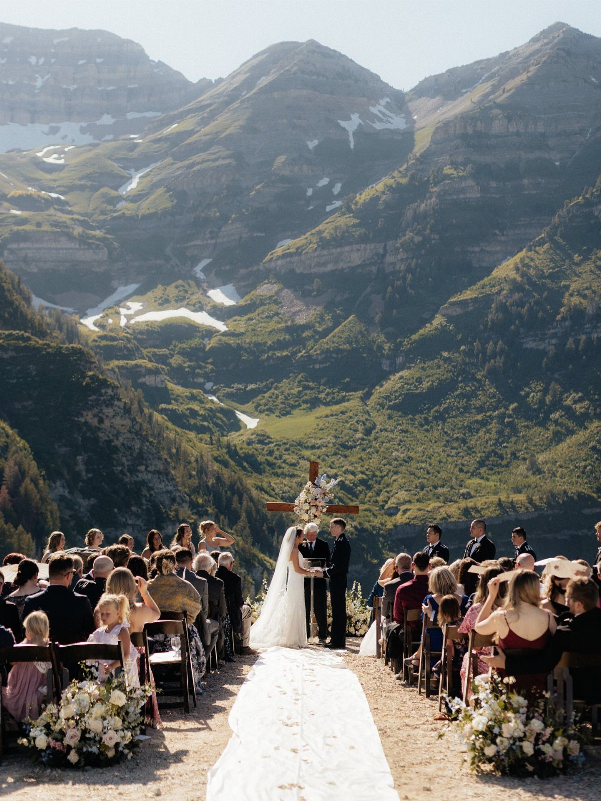 Wedding ceremony on a mountain cliff with a stunning alpine valley backdrop.