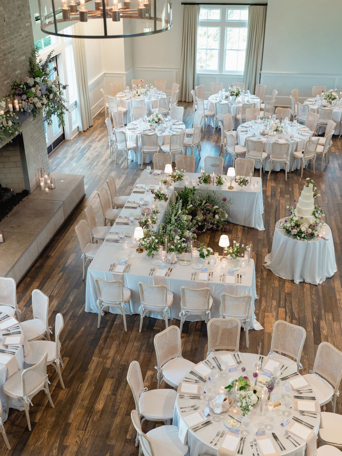 Wedding reception setup with white tables, floral arrangements, and wooden floors in a museum.