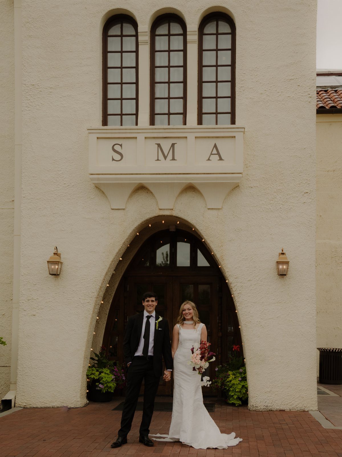 Bride and groom posing in front of the Springville Museum of Art entrance