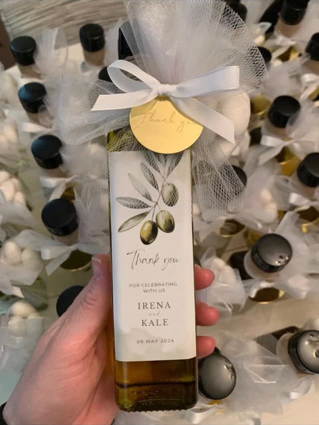 Small olive oil bottle with white tulle bow and personalized wedding thank you label