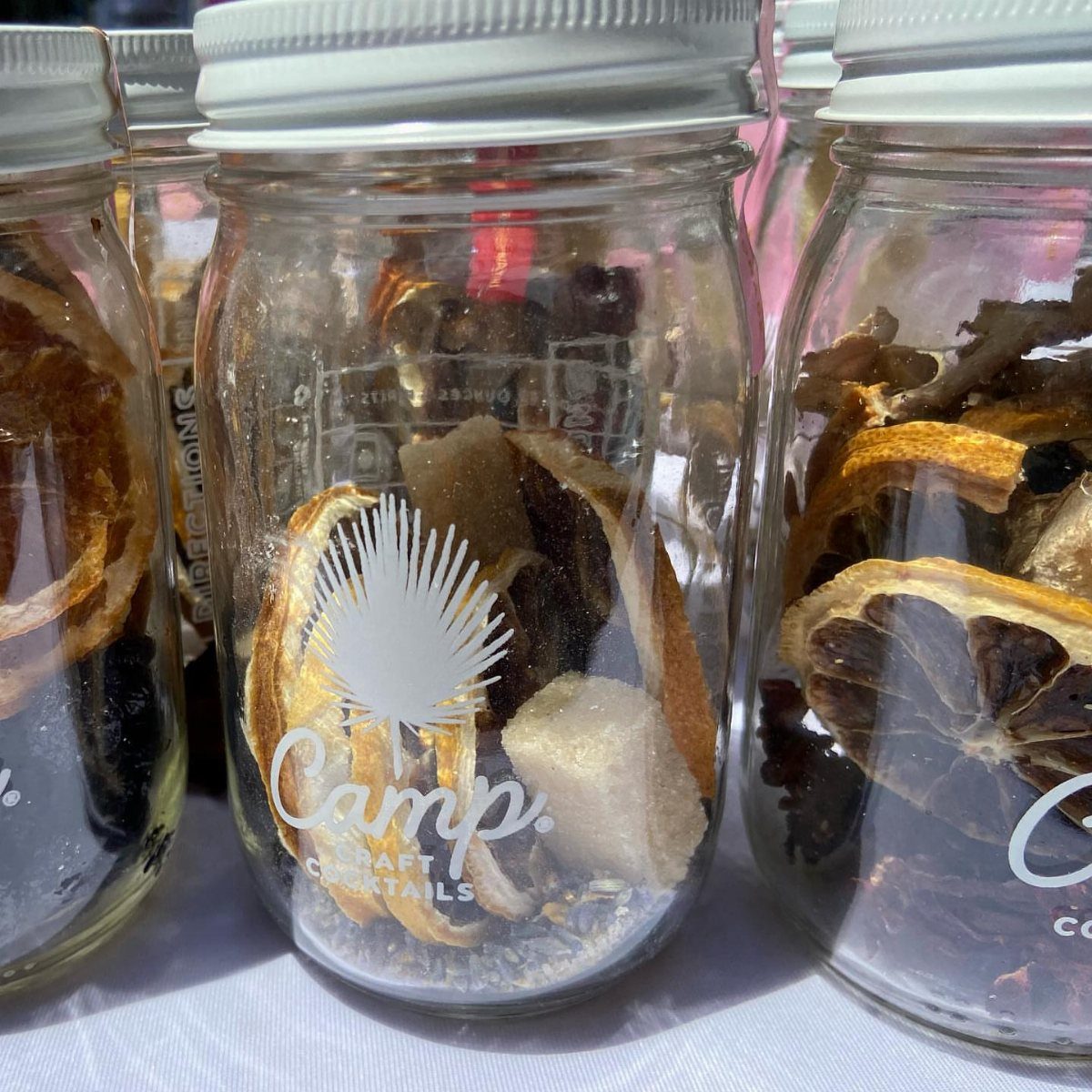 Glass jars filled with dried citrus and sugar for DIY cocktail kits.