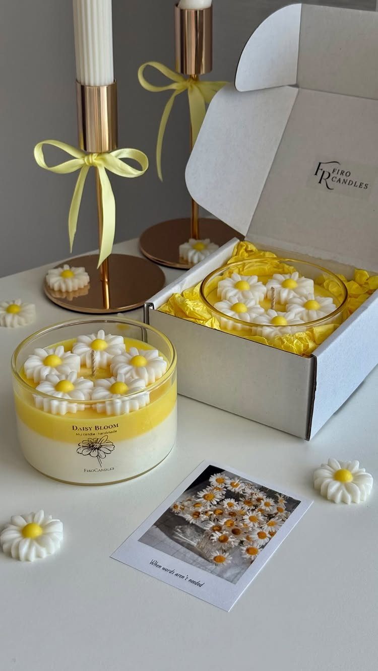 Daisy themed candles in glass jars with a white gift box and gold holders