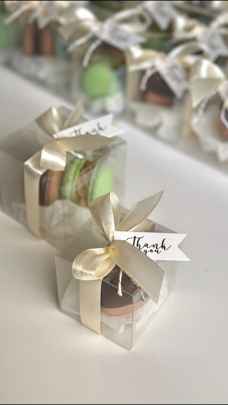 Macarons in clear gift boxes with gold ribbons and thank you tags.