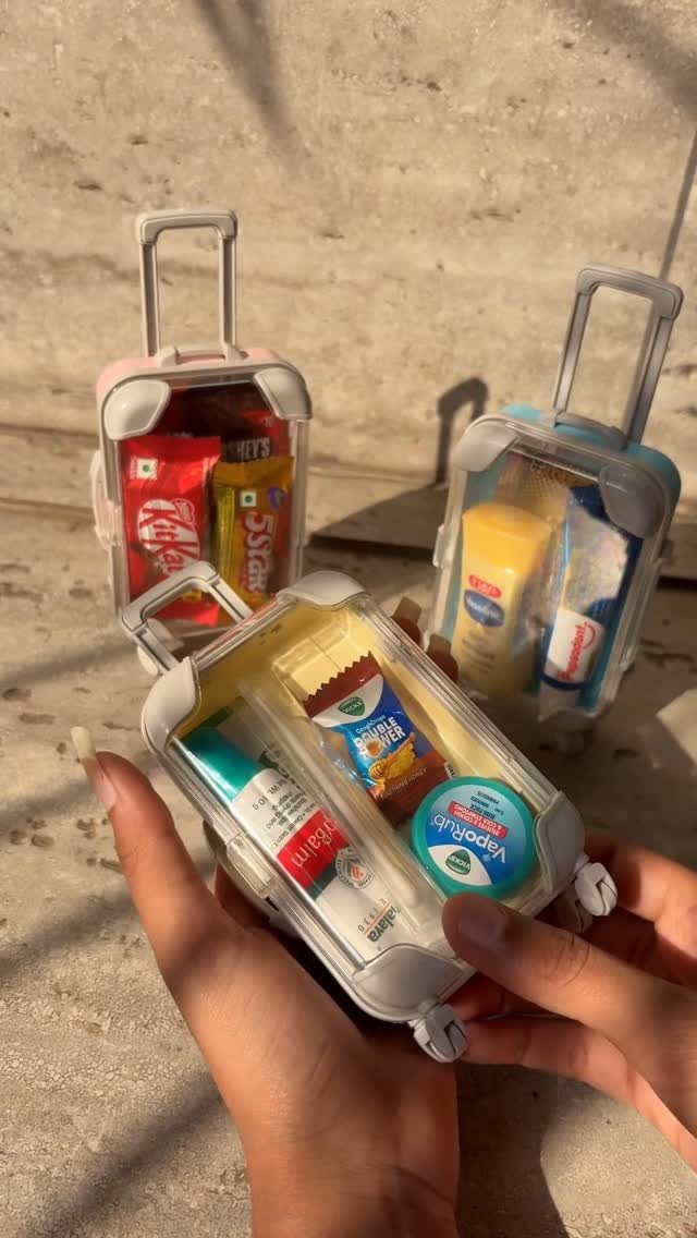 Miniature clear suitcases filled with small treats and toiletries as wedding favors.