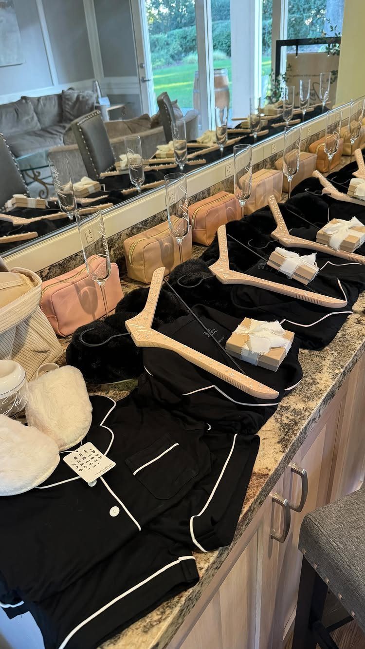 Black satin pajamas, white slippers, and peach pouches arranged on a granite counter.