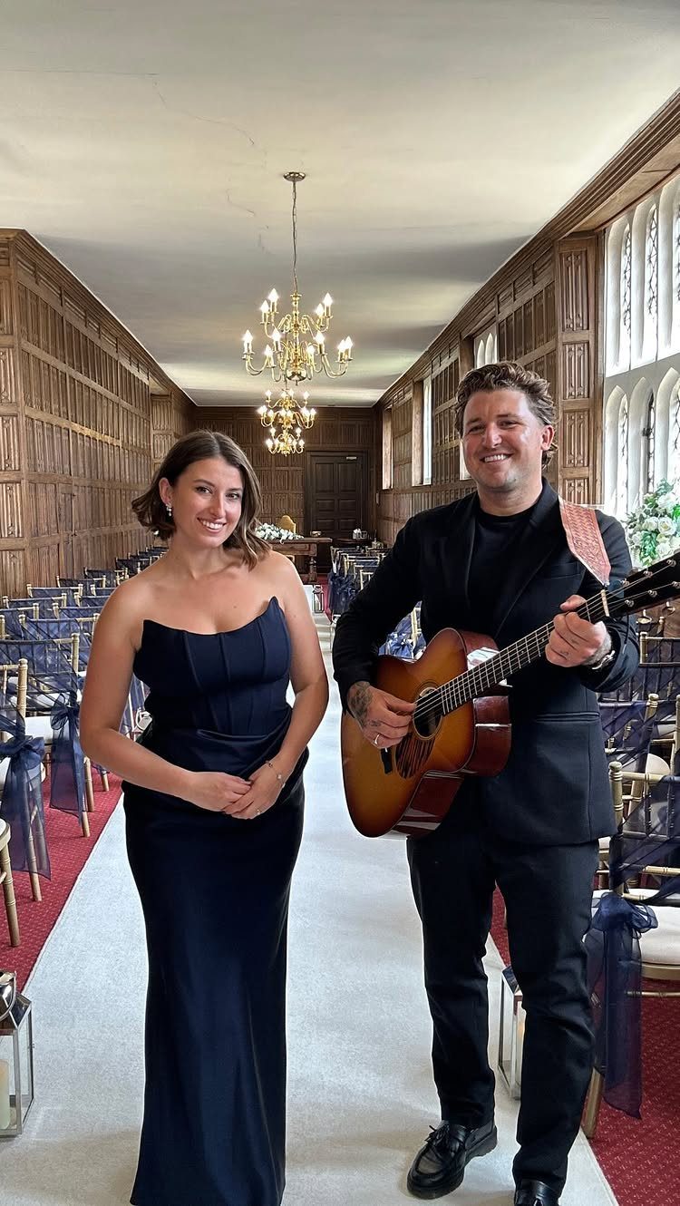 Musicians with an acoustic guitar posing in a wood-paneled wedding ceremony venue.