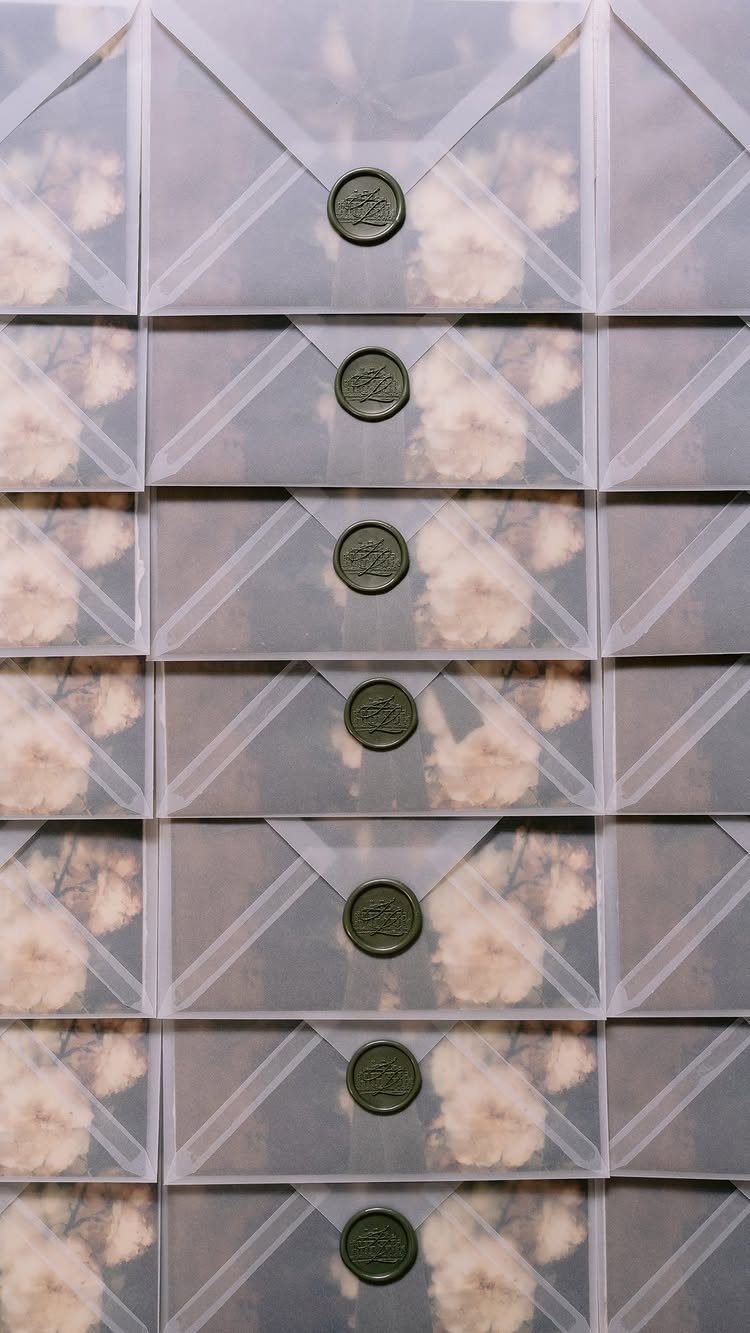 Translucent vellum paper envelopes sealed with dark green wax seals over floral prints.