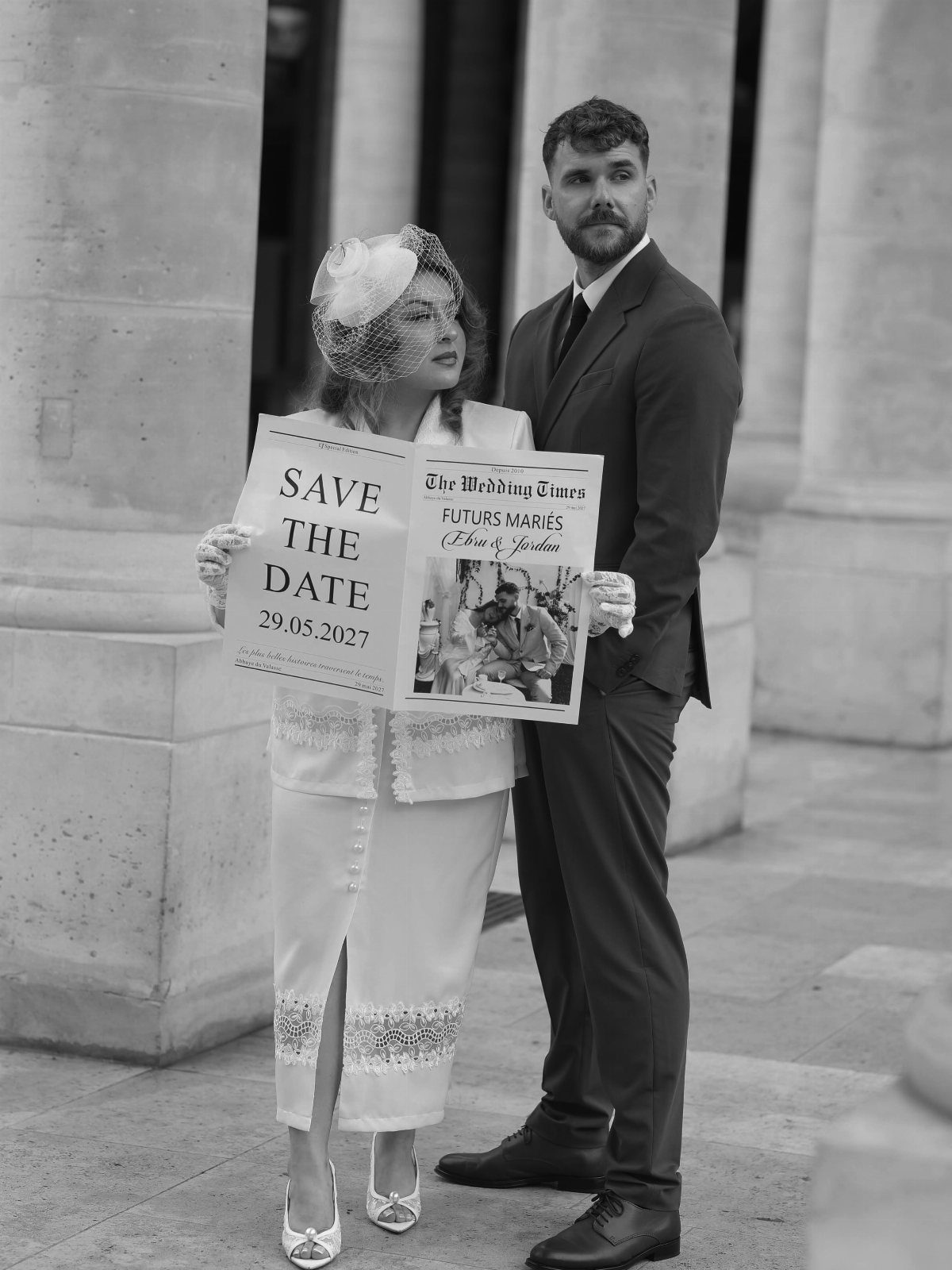 Couple in vintage clothing holding a save the date sign in black and white.