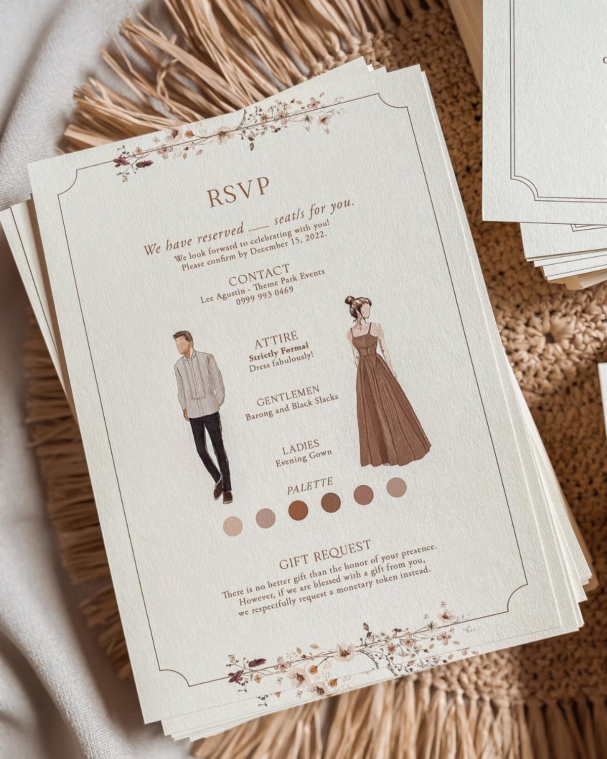 Cream RSVP cards with floral borders and formal attire illustrations on woven mat