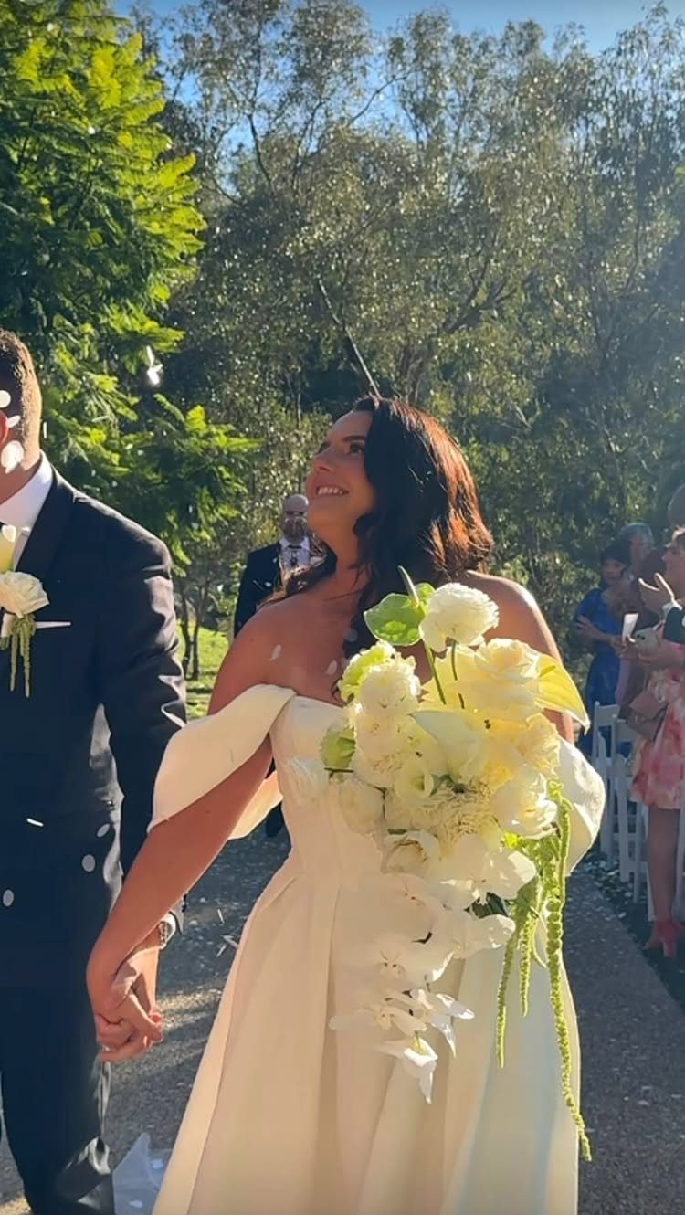 Bride in white gown and groom in suit walking together outdoors after wedding