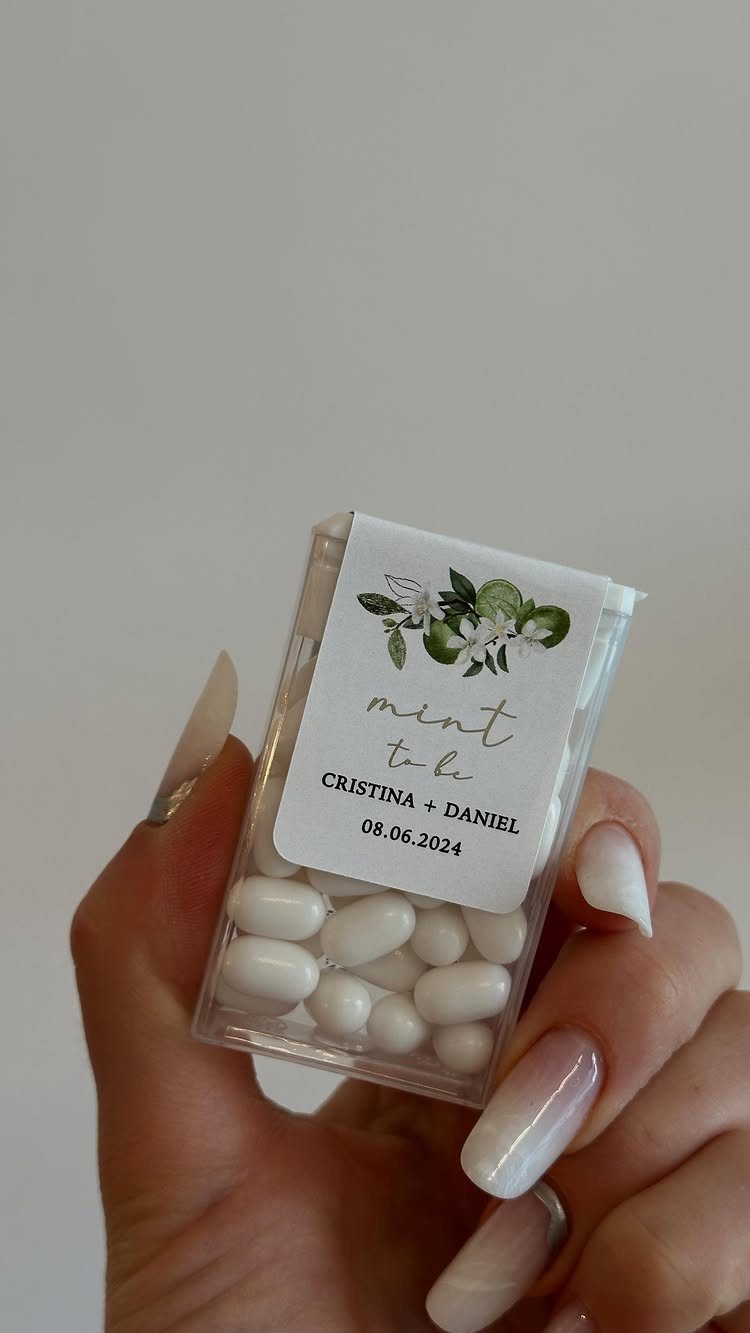 Small clear box of white mints with a personalized wedding label held by hand.