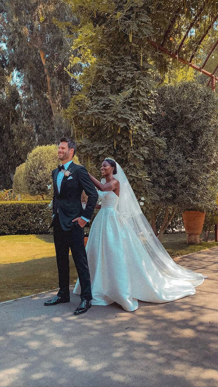 Bride in white gown touching groom's shoulder during a private first look outdoors.