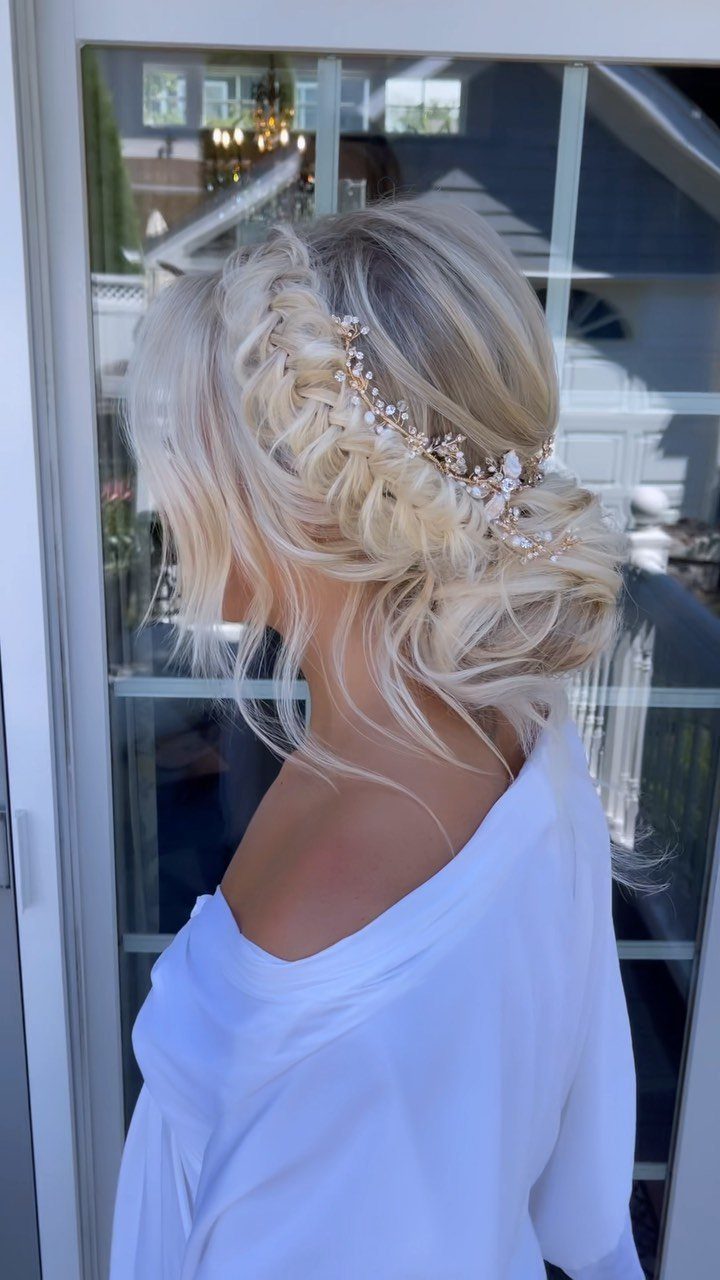 Blonde woman with an intricate braided wedding updo and gold floral hair accessory.
