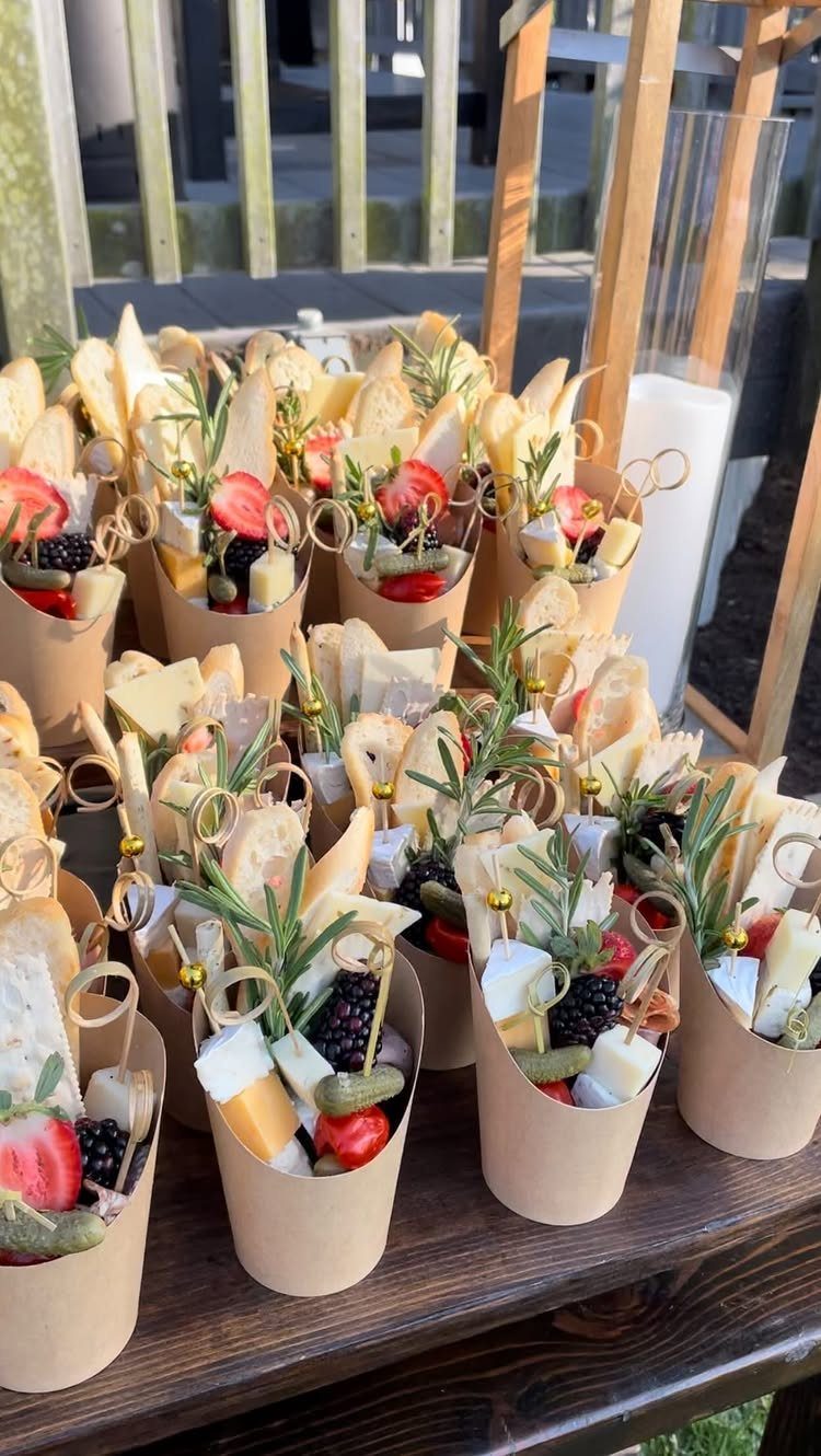 Individual charcuterie cups with cheese, fruit, and bread on a wooden table.