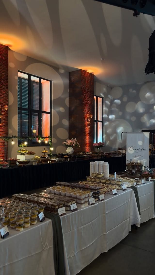 Dessert buffet table with small treat cups and sweets in an event space.