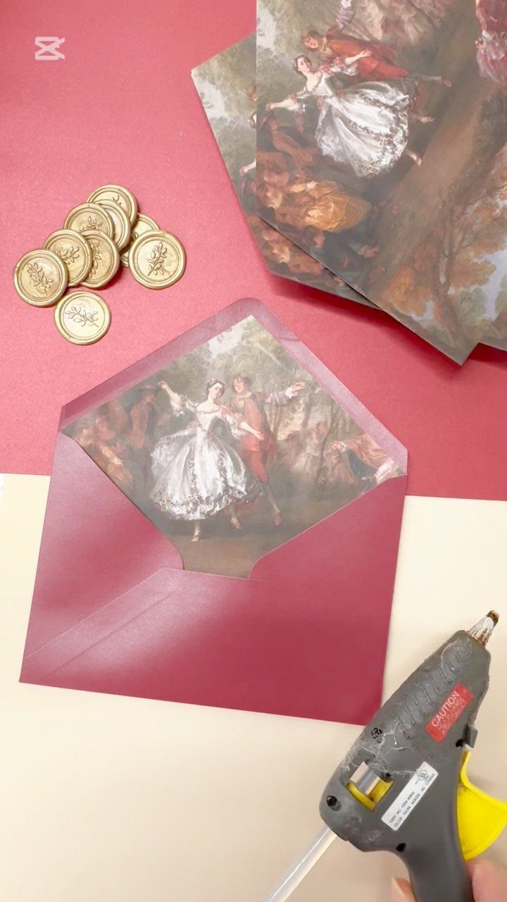 Burgundy envelope with a classical painting liner, gold wax seals, and glue gun.