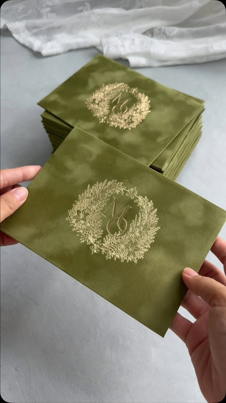 Moss green envelopes with gold foil embossed floral wreaths and monograms.