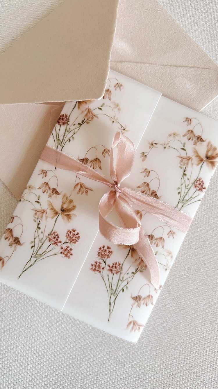 Floral wedding invitation wrapped in vellum and tied with a rose satin ribbon.