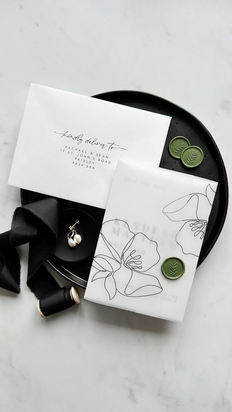 Wedding invitation suite with a floral vellum wrap and green wax seals.