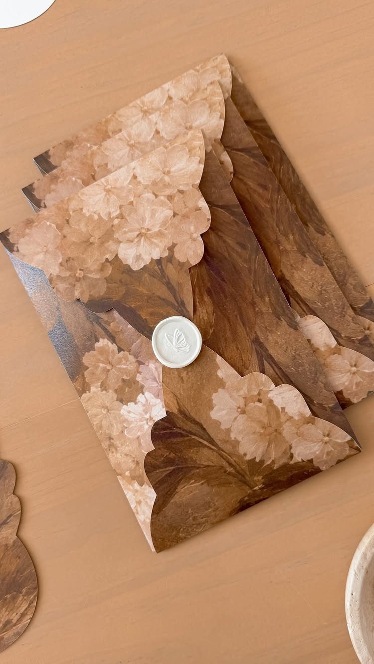 Floral patterned envelope sealed with a small white wax seal on tan background
