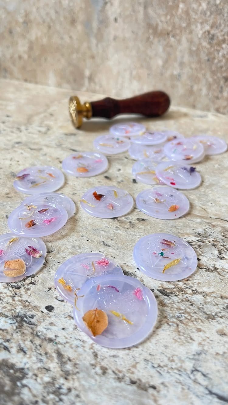 Translucent white wax seals with dried flower petals and a wooden stamp.