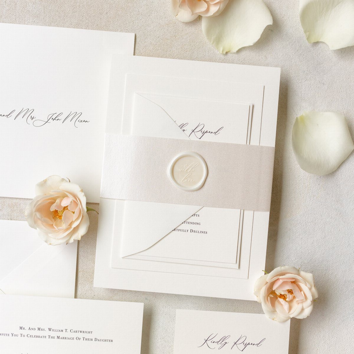 White wedding invitation with a grey ribbon belly band and white wax seal.