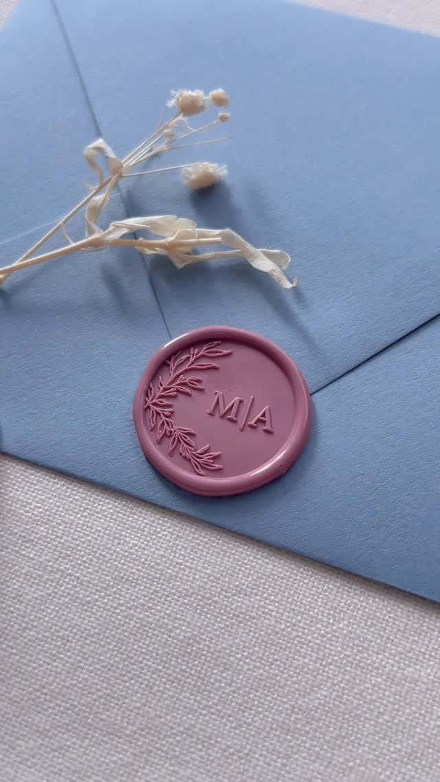 Purple wax seal with initials M|A on a light blue envelope flap