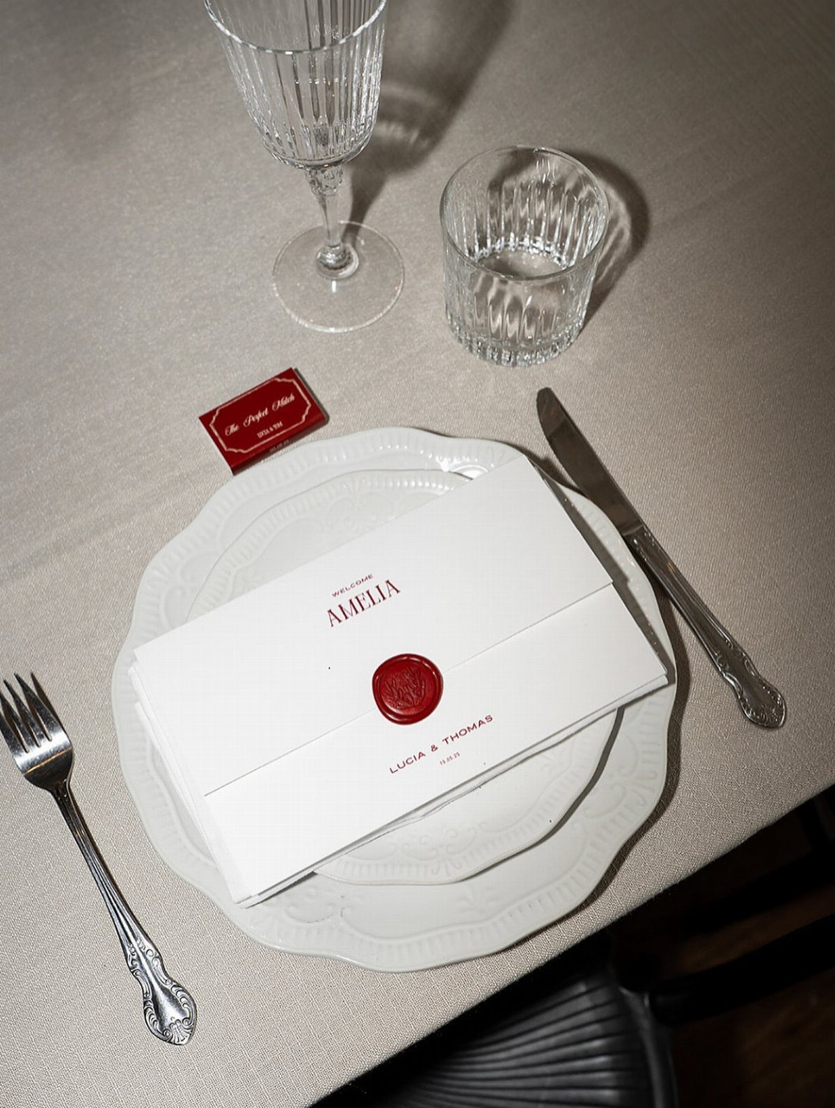 White folded menu card with a red wax seal on a dinner plate
