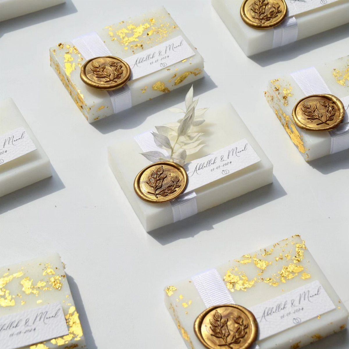 White soap bars with gold flakes wrapped in bands with gold wax seals.