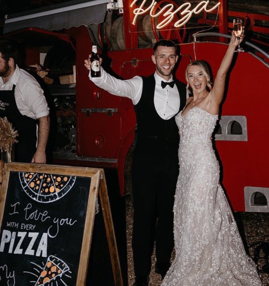 Bride and groom posing in front of a red pizza truck at night