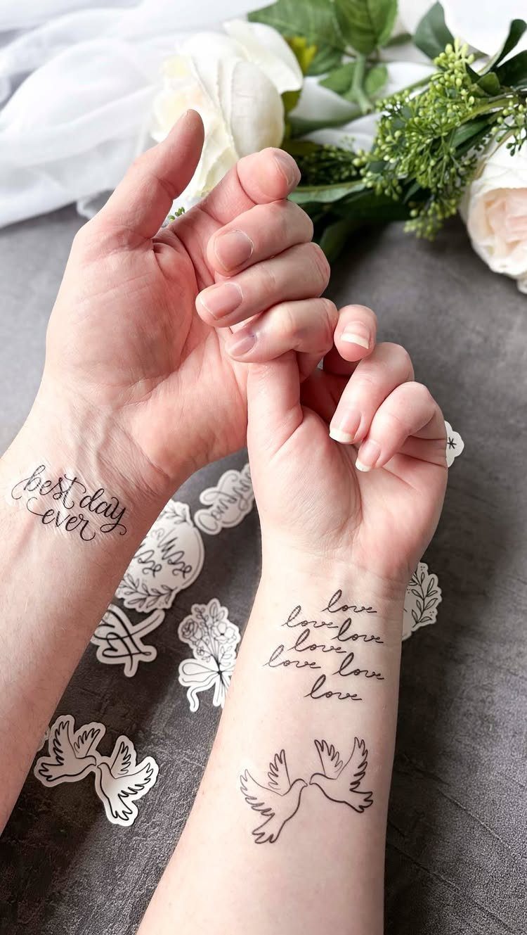 Two forearms with temporary wedding tattoos featuring doves and romantic text.