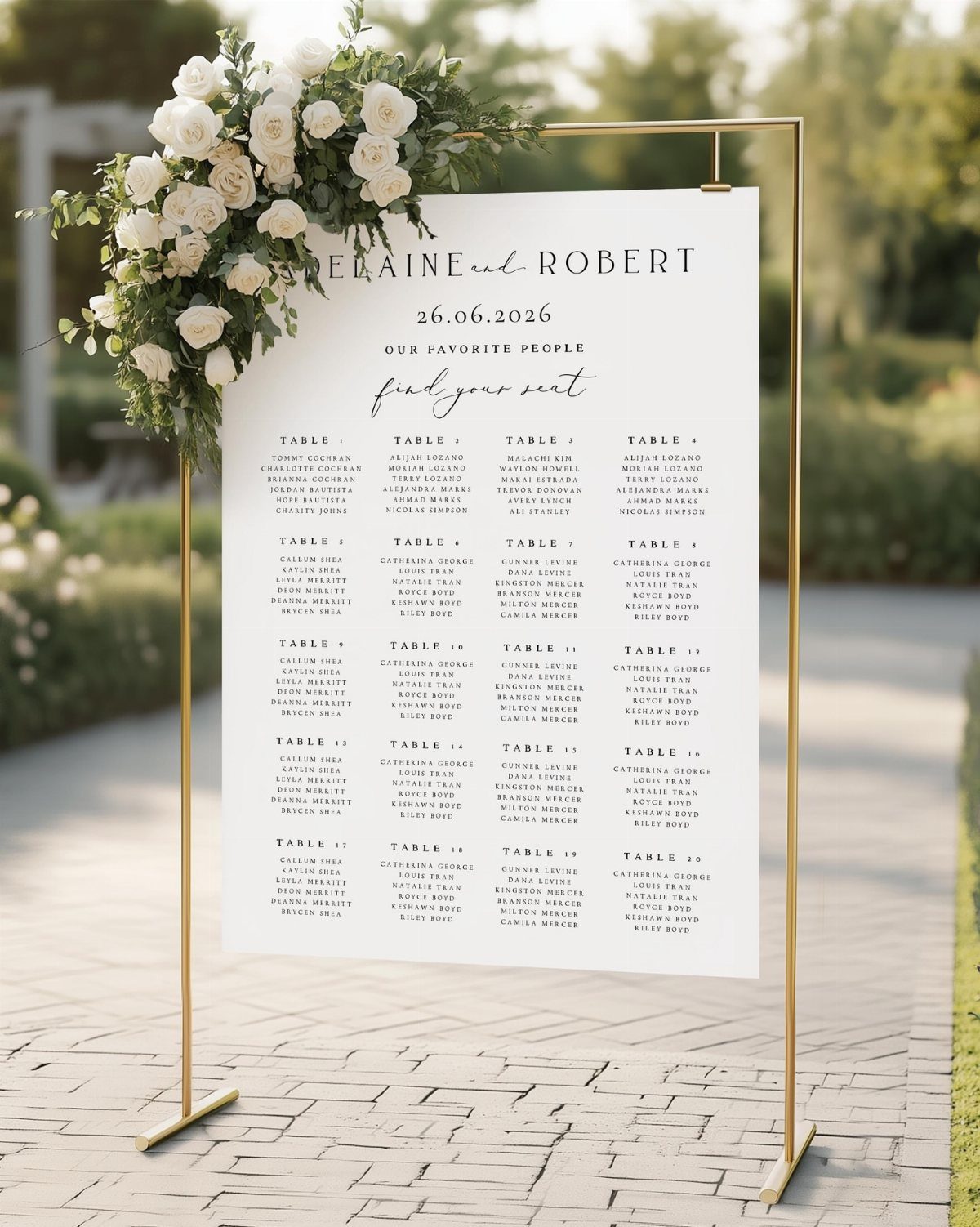 Wedding seating chart on a gold frame decorated with white roses and greenery.
