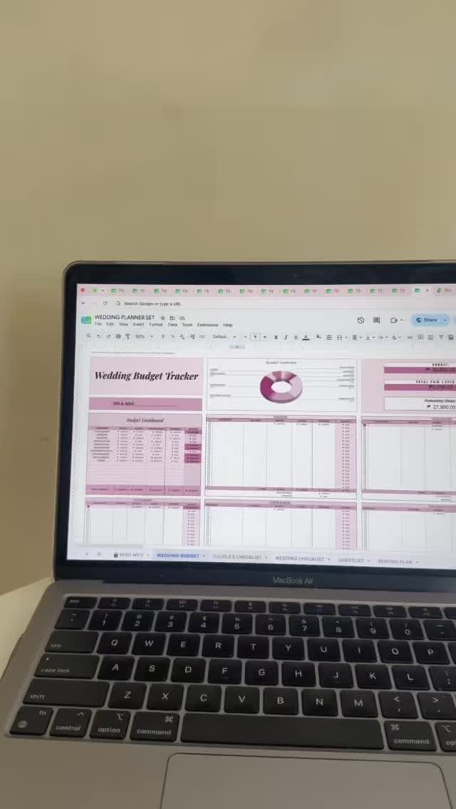 Laptop screen showing a pink and white digital wedding budget tracker spreadsheet.