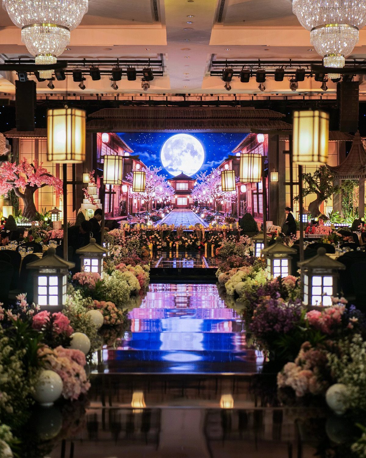 Opulent wedding venue with a reflective blue aisle and a large moon backdrop.