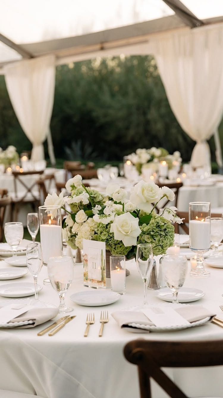Elegant wedding table setting with white flowers, gold cutlery, and glowing candles.