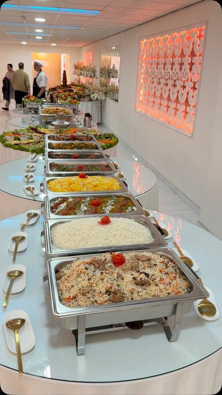 Buffet line with various rice and meat dishes in silver chafing dishes.