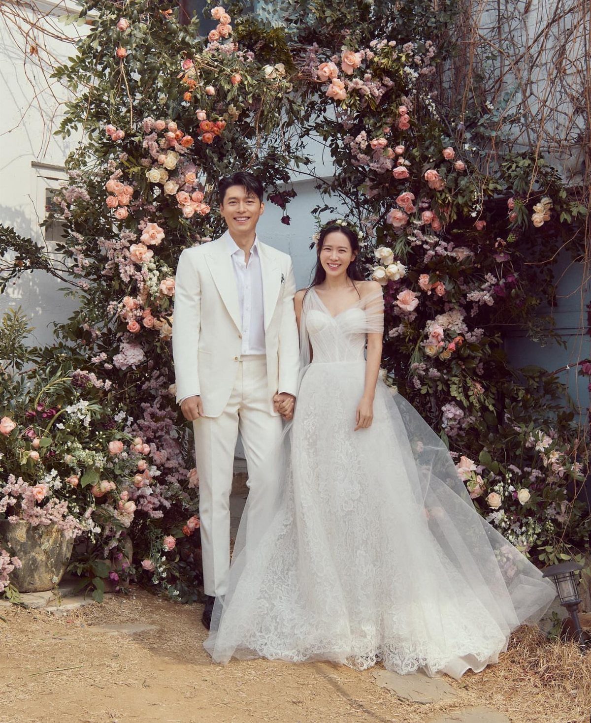 Bride in a white lace wedding dress and groom in a white suit.