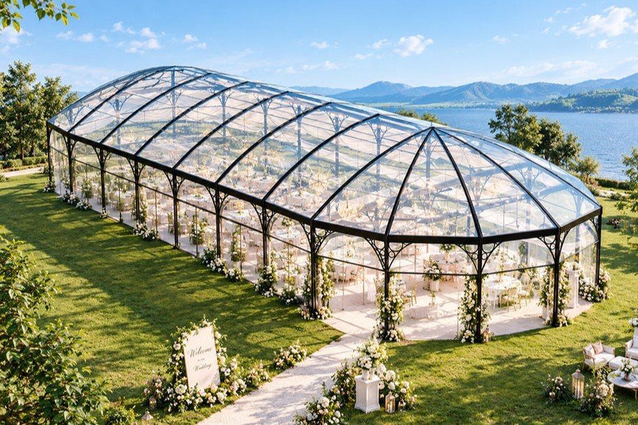 Glass marquee wedding venue on a green lawn overlooking a lake and mountains
